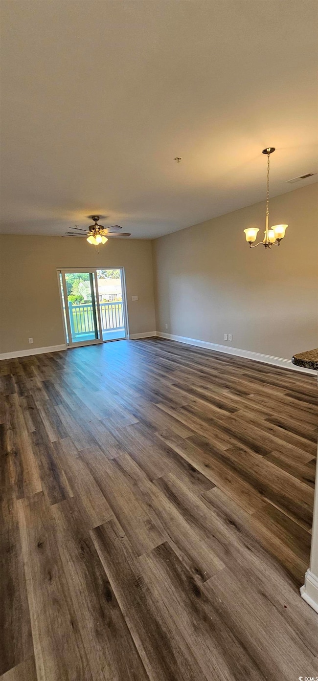 Unfurnished living room featuring dark wood-style floors, a chandelier, and ceiling fan