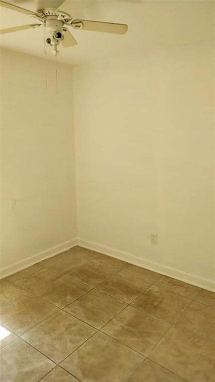 Spare room featuring ceiling fan and light tile pa