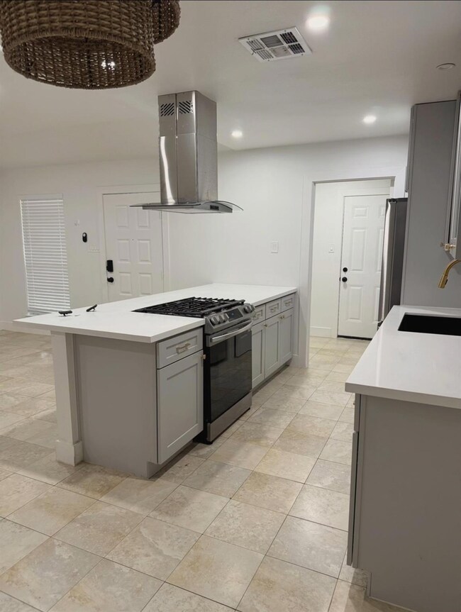 Kitchen featuring island range hood, gray cabinet