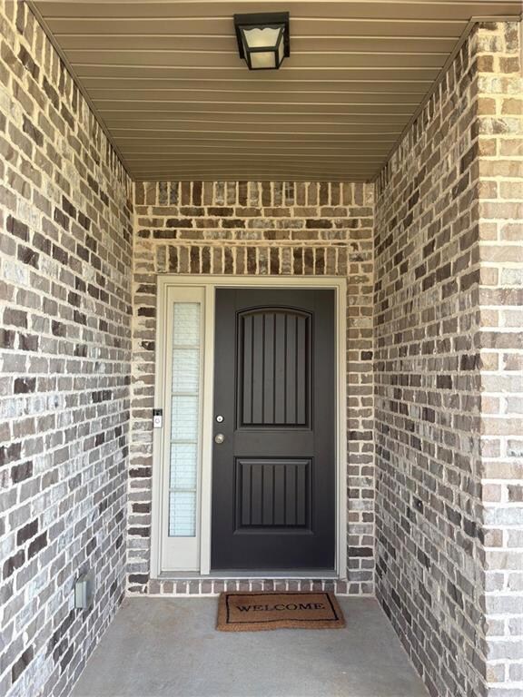 Doorway to property featuring brick siding