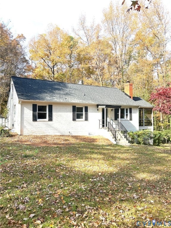 Ranch-style home featuring a chimney, a front lawn, and brick siding