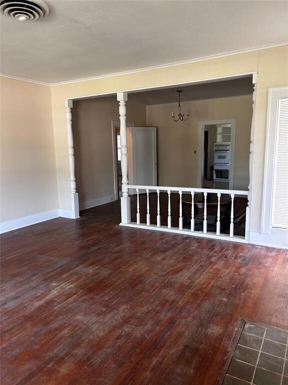 Spare room with an inviting chandelier, dark hardw