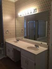 Bathroom with toilet, wallpapered walls, a sink, a