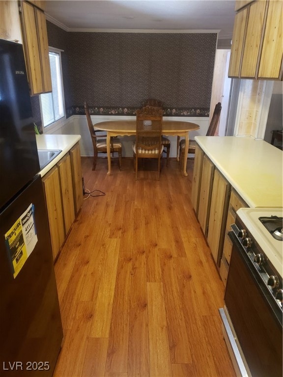 Kitchen featuring fridge, range, light wood finish