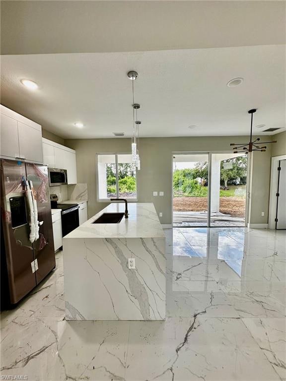 Kitchen with pendant lighting, sink, a kitchen island with sink, white cabinetry, and stainless steel appliances