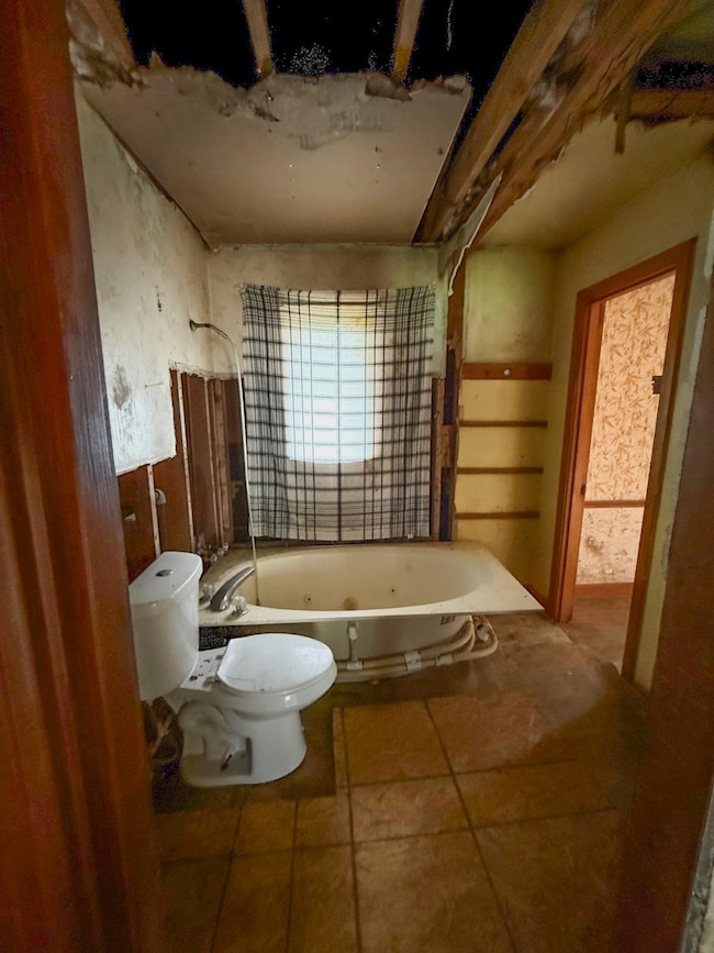Bathroom featuring toilet, a washtub, and tile pat
