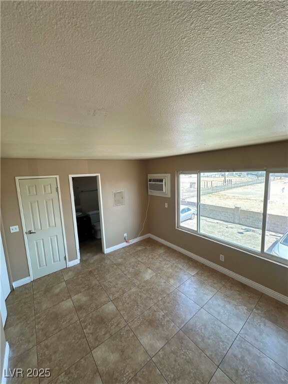Tiled spare room featuring a textured ceiling, an