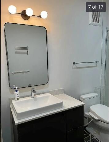 Full bath featuring vanity, toilet, and a shower