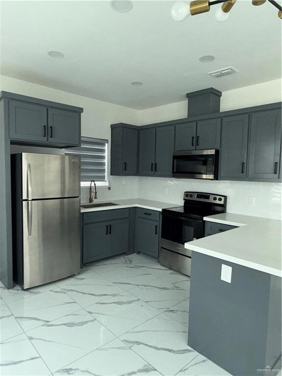 Kitchen with fridge, range, a sink, gray cabinets, and light marble finish flooring
