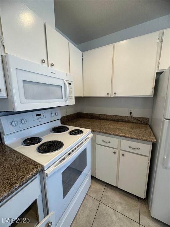 Kitchen with white appliances, light tile patterne