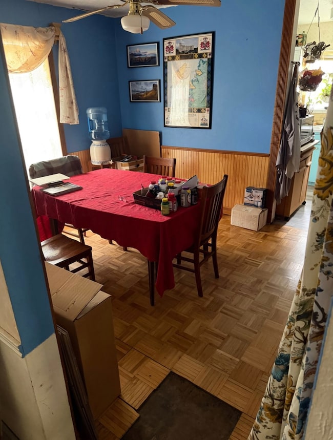 Dining area with wainscoting, wood walls, and ceiling fan