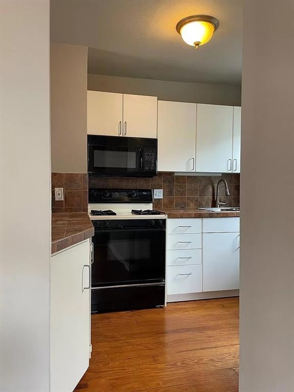 Kitchen with gas stove, black microwave, white ca