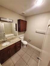 Bathroom with vanity, tile patterned floors, toilet, and baseboards