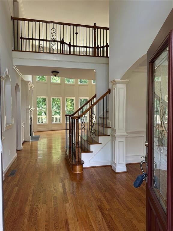 Entryway with a high ceiling, arched walkways, wood finished floors, stairs, and baseboards