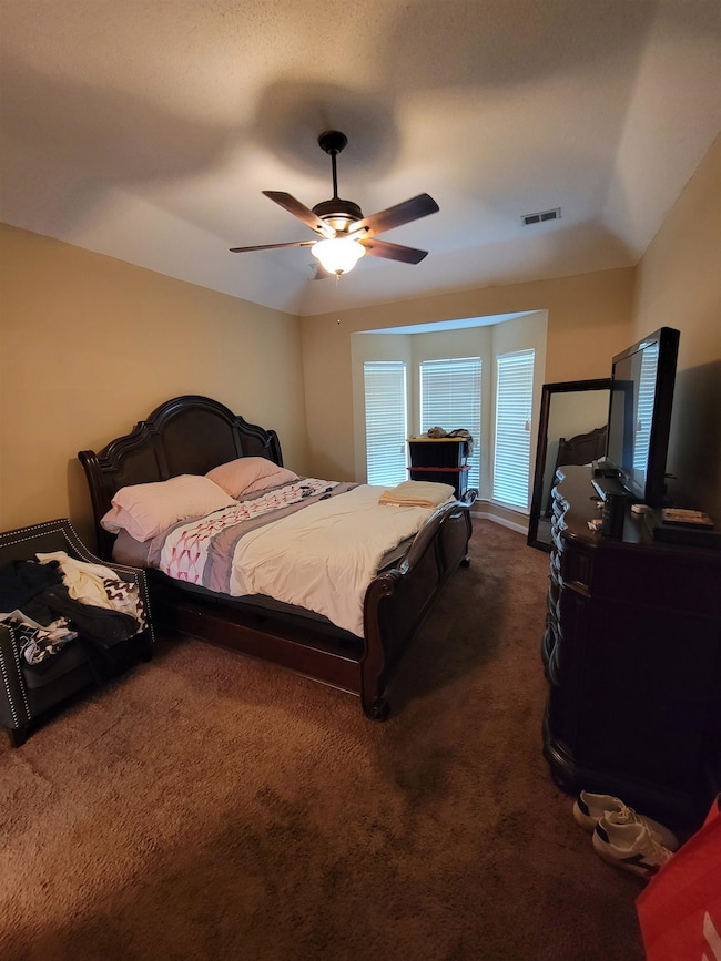Bedroom featuring dark carpet and a ceiling fan