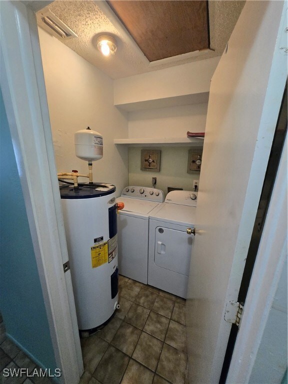 Laundry room featuring water heater, dark tile pat