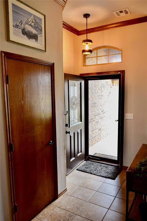 Tiled foyer with crown molding and baseboards