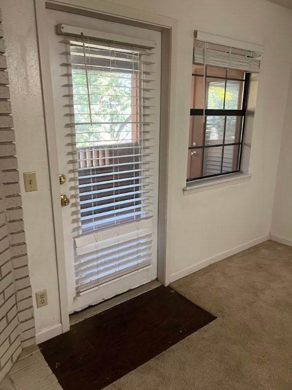 Doorway featuring carpet floors and baseboards