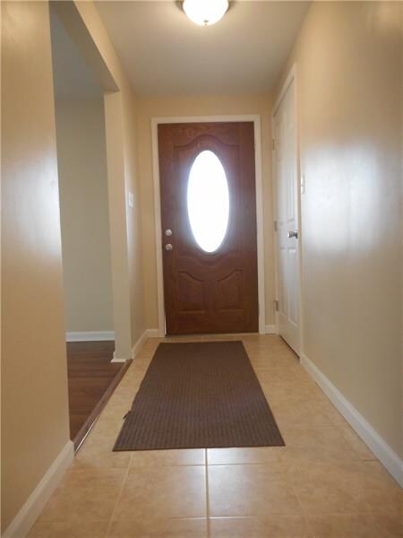 Ceramic tiled entry hall with coat closet