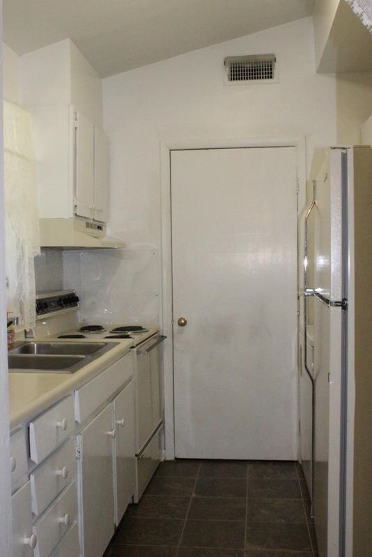 The kitchen features plenty of cabinet space, a range/oven, and access to the utility room.