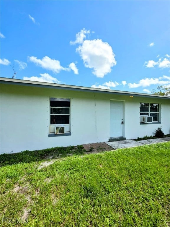 Property entrance with stucco siding and a lawn