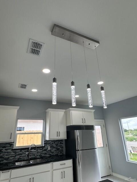 Kitchen featuring refrigerator, dark countertops, decorative backsplash, recessed lighting, and white cabinetry