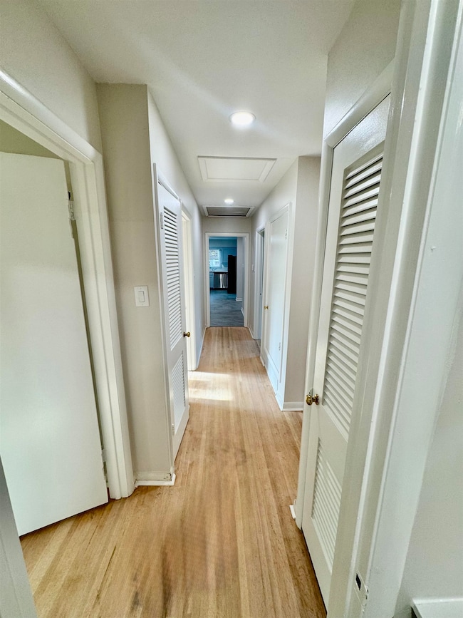 Hallway featuring light wood-style floors, attic access, and recessed lighting