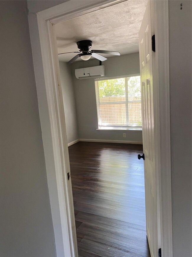 Unfurnished room featuring a textured ceiling, dark wood-type flooring, ceiling fan, and a wall unit AC