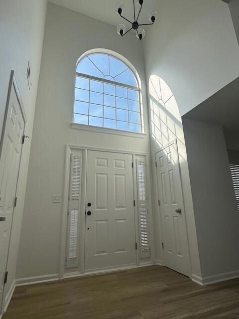 Entrance foyer with a high ceiling, dark wood-style flooring, and a chandelier