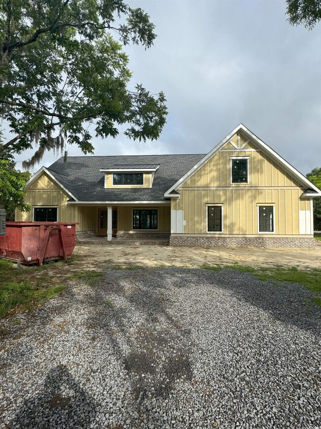 View of front facade with a shingled roof and board and batten siding