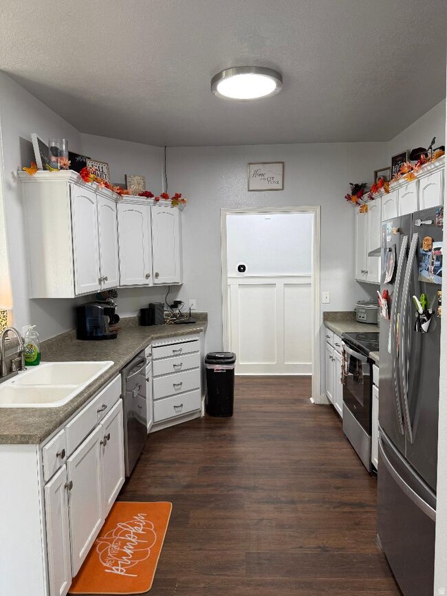 Kitchen featuring white cabinetry, appliances with stainless steel finishes, dark wood-type flooring, and a textured ceiling
