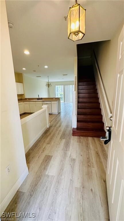 Stairway with hardwood / wood-style flooring and an inviting chandelier