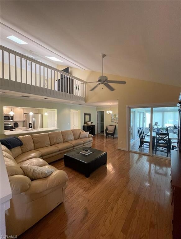 Living room featuring ceiling fan and high vaulted