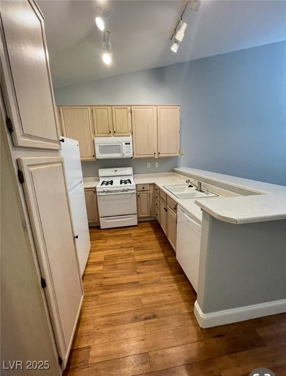 Kitchen featuring white appliances, a sink, light