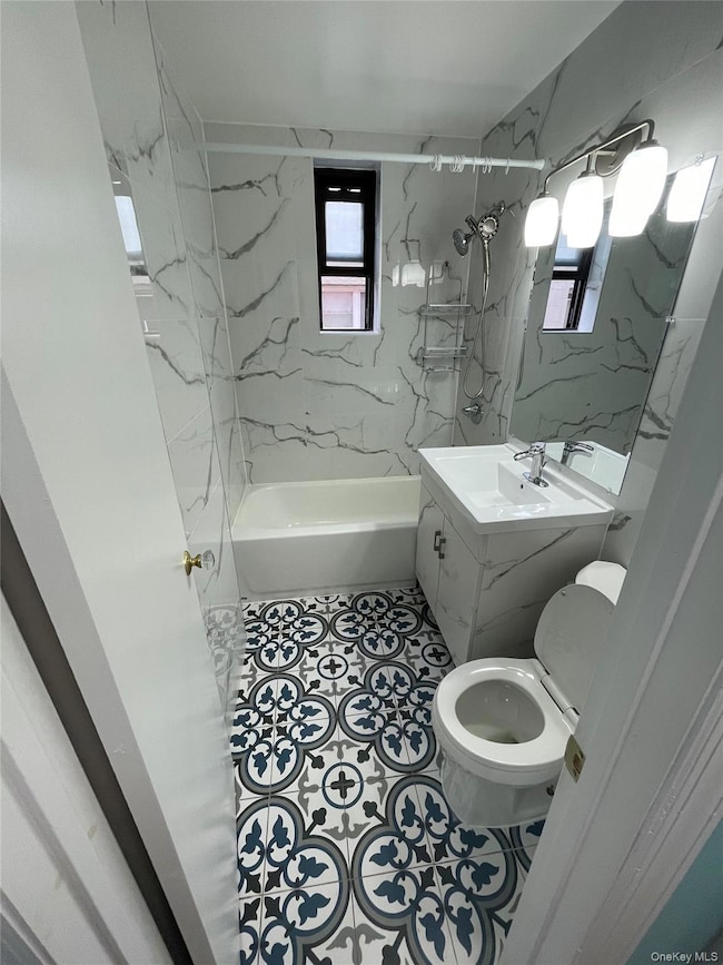 Bathroom featuring washtub / shower combination, vanity, and tile patterned floors