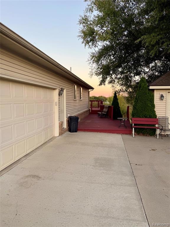 View of side of property featuring a wooden deck, a garage, and driveway