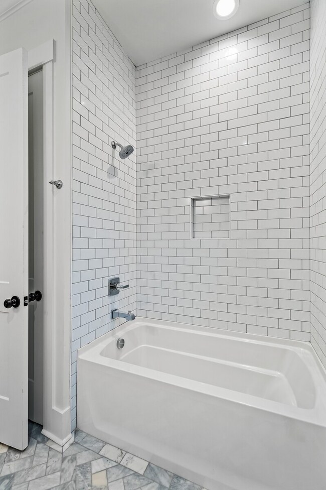 Custom details continue into this bathroom as well, with beautiful herringbone pattern marble tile floors and a tub/ shower with a floor-to-ceiling subway tile surround.