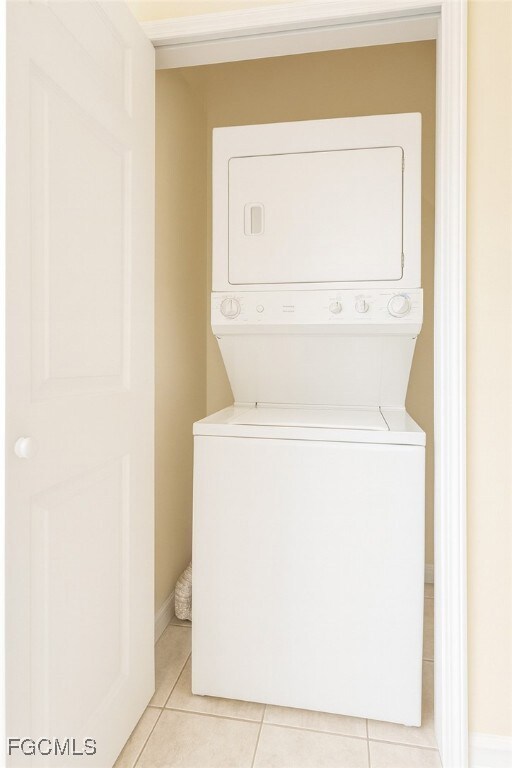 Laundry area with light tile patterned floors and stacked washer / dryer