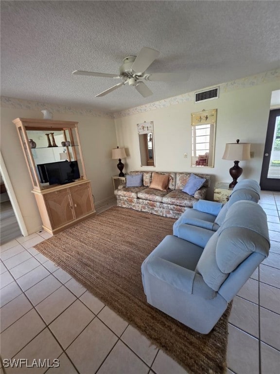 Living room featuring light tile patterned flooring, a textured ceiling, and ceiling fan