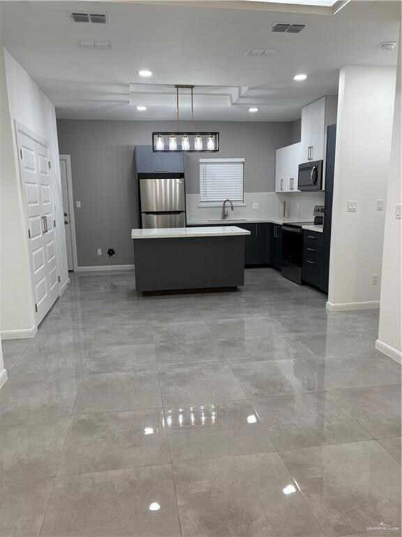 Kitchen with range, refrigerator, light countertops, a center island, and a sink