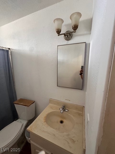 Bathroom featuring toilet, vanity, and a shower wi