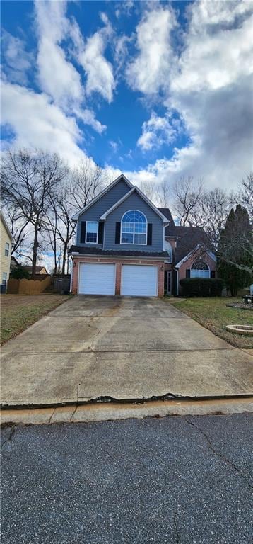 Traditional-style home with an attached garage, brick siding, and driveway