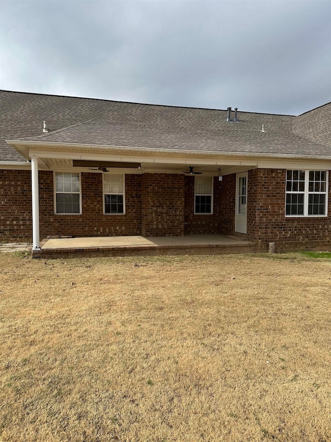 Rear view of house with a patio, a yard, and brick siding