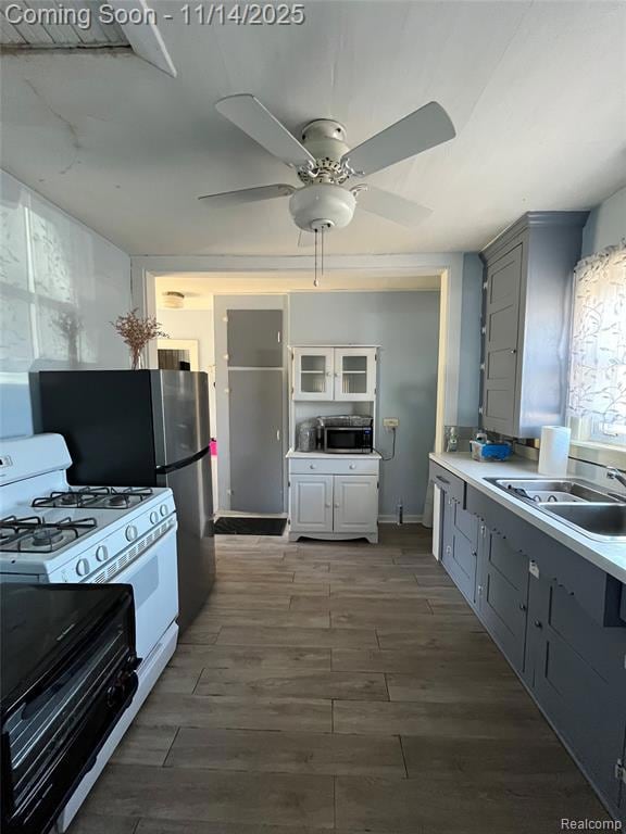 Kitchen with gray cabinets, white gas range oven, light wood-style floors, light countertops, and electric range