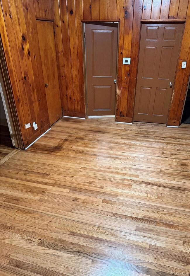Entryway with light wood-type flooring and wood walls