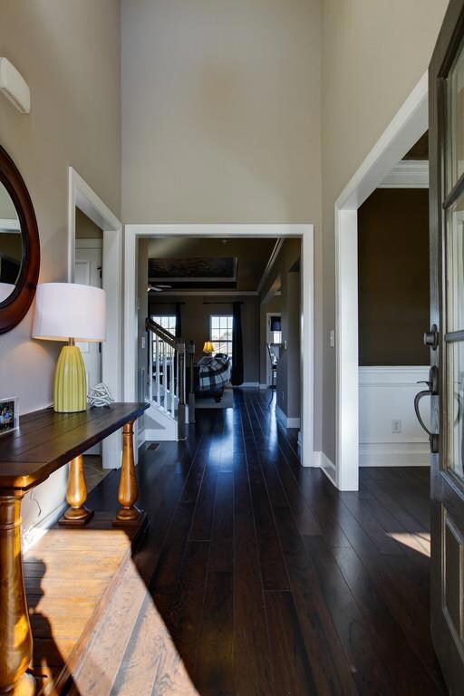 The front door with glass window invites you into the 2-Story Foyer with hardwood flooring, plant shelf with a window above that floods the space with natural light, setting the tone for the rest of the home.
