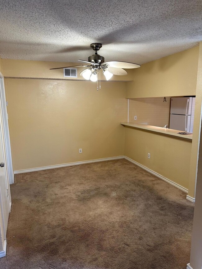 Empty room with a textured ceiling, carpet floors,