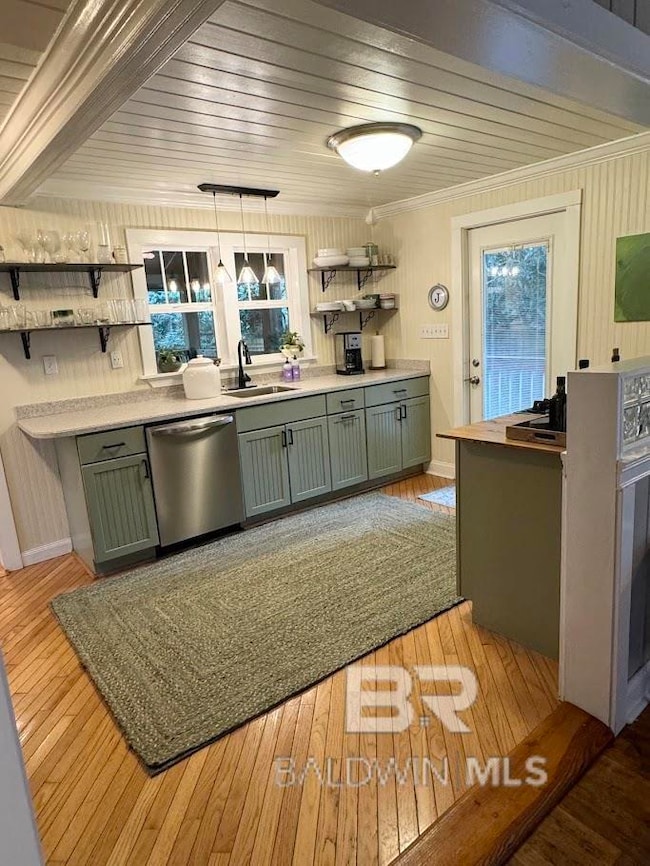 Kitchen featuring dishwasher, sink, crown molding, light wood-type flooring, and decorative light fixtures