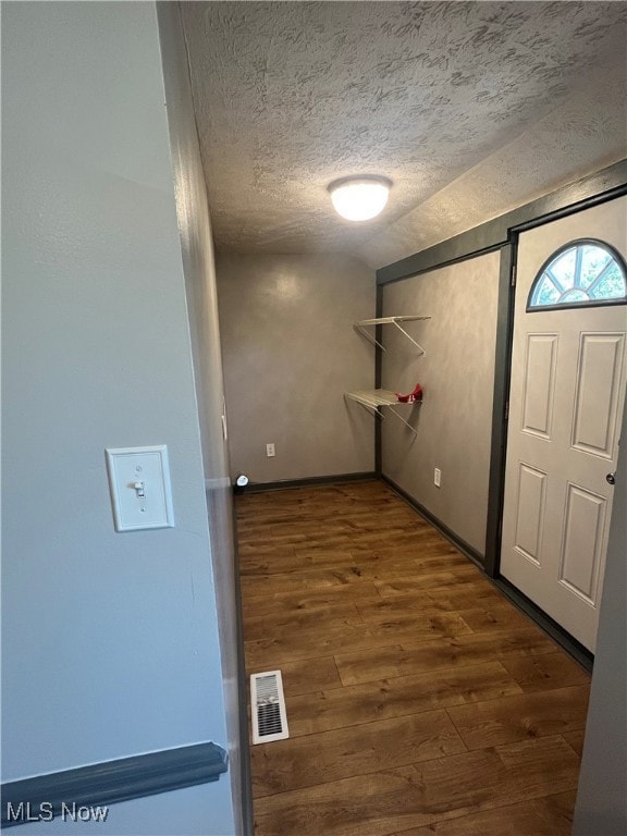 Hallway with a textured ceiling and dark wood-style floors