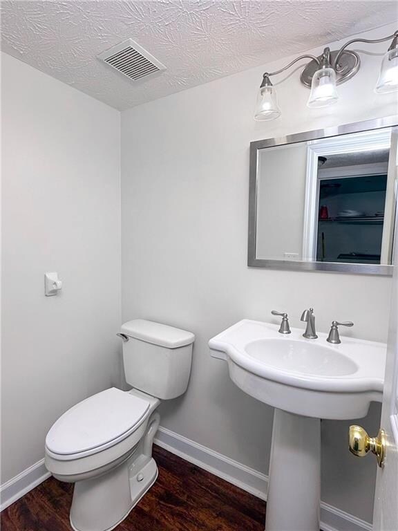 Half bath featuring visible vents, baseboards, toi